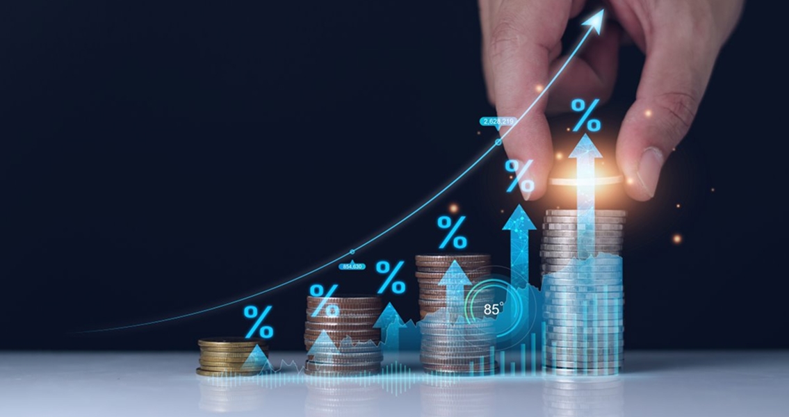 A hand stacks coins in ascending order with blue percentage symbols and upward arrows, indicating financial growth against a dark background.
