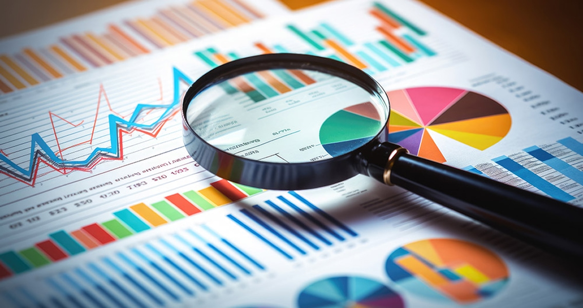 A magnifying glass hovers over colorful charts and graphs, with pie charts, bar graphs, and line graphs, conveying data analysis and focus.