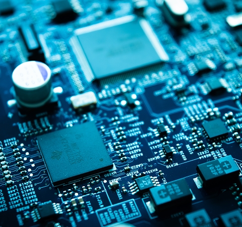Close-up of a blue-toned circuit board with various microchips and electronic components. The image conveys a modern, technological feel.