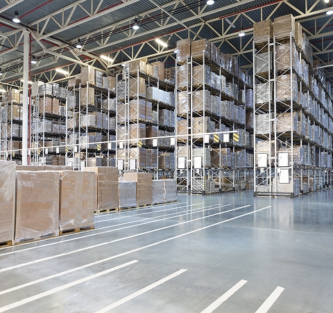 Large warehouse interior with high shelves filled with stacked boxes. Brightly lit and organized, conveying a sense of efficiency and order.